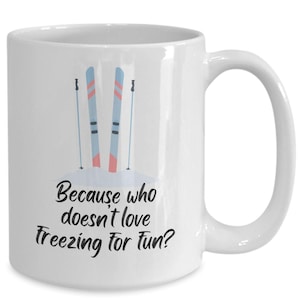 May include: White ceramic coffee mug featuring a black and white illustration of skis and ski poles. The text "Because who doesn't love freezing for fun?" is printed on the mug.