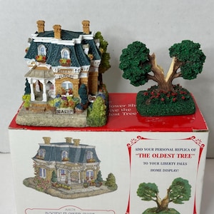 May include: A miniature replica of Rosie's Flower Shop, a two-story brick building with a green roof and a sign that reads "Rosie's Flowers". The building is surrounded by flowers and greenery. The box also includes a miniature replica of "The Oldest Tree" from Liberty Falls.