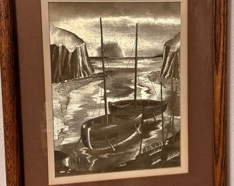 May include: A framed black and white print of two boats docked in a harbor. The boats are in the foreground, with a rocky shore and water in the background. The print is framed in a dark wood frame.