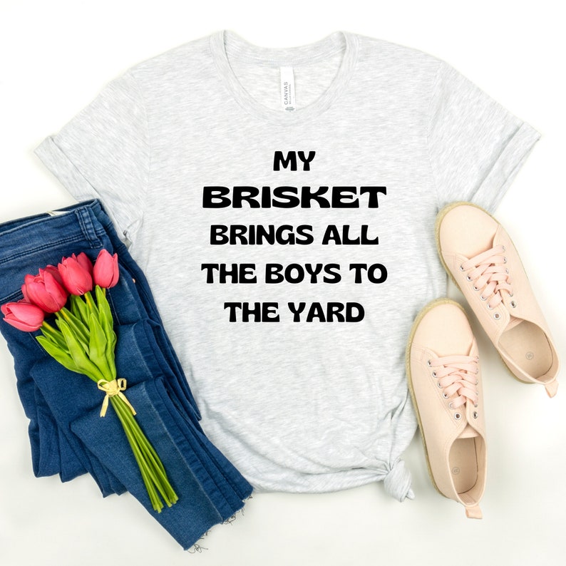 May include: A gray t-shirt with the text "My Brisket Brings All The Boys To The Yard" printed in black.