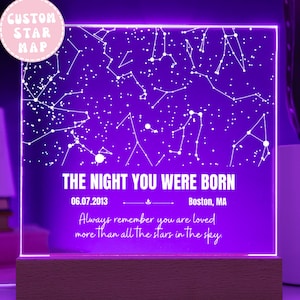 May include: A custom star map night light with a purple glow. The text "THE NIGHT YOU WERE BORN" is displayed, along with a date and location. The phrase "Always remember you are loved more than all the stars in the sky" is also included.