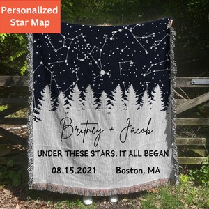 May include: A personalized star map throw blanket with a navy blue background and white constellations. The blanket features the names "Britney + Jacob" and the text "Under these stars, it all began 08.15.2021 Boston, MA".