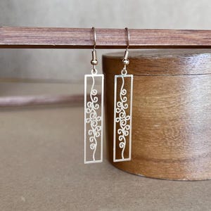 May include: Gold filigree rectangle earrings with a delicate floral design.