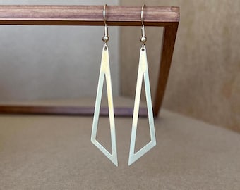 May include: A pair of gold-toned geometric earrings with a triangle shape. The earrings are long and dangle.