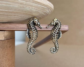 May include: A pair of gold-toned seahorse earrings. The seahorses are detailed with a delicate, openwork design.
