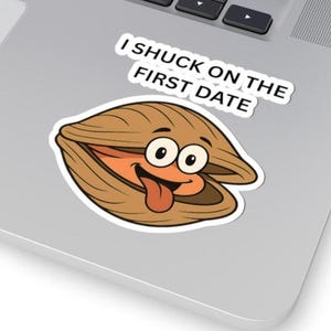 May include: A sticker featuring a cartoon clam with a smiling face and a tongue sticking out. The clam is brown with orange and white accents. The text "I SHUCK ON THE FIRST DATE" is above the clam.