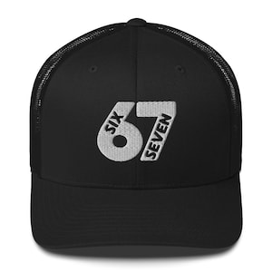 Könnte beinhalten: Schwarze Trucker-Cap mit gebogenem Schirm und Mesh-Rückseite. Auf der Vorderseite ist der gestickte Text "SIX 67 SEVEN" in Weiß zu sehen. Ein klassischer Baseballkappen-Stil.