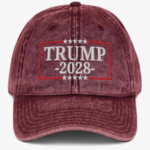 May include: A red vintage baseball cap with a white embroidered logo that says "TRUMP -2028- ". The logo is surrounded by a red border and five white stars on each side.
