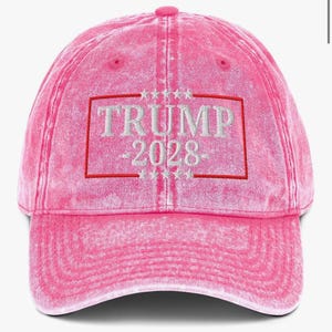 May include: Pink distressed baseball cap with white embroidered text that reads "TRUMP 2028" inside a red rectangle with white stars above and below the rectangle.