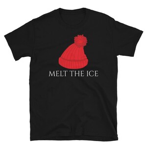 May include: Black t-shirt featuring a red knit cap graphic with a pom-pom. The text "MELT THE ICE" is printed in white below the graphic. The shirt is made of a soft material.