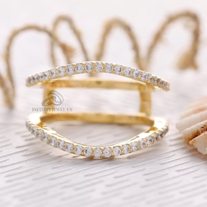 May include: A gold ring with two bands set with small clear stones. The ring is designed to fit over another ring.