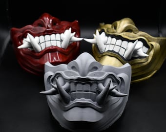 May include: Three decorative masks with sharp teeth and a menacing expression. The masks are painted in red, gold, and gray.