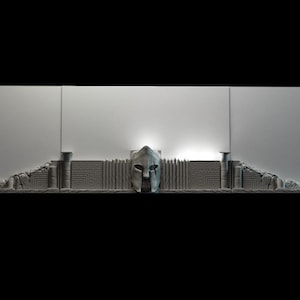 May include: A gray, 3D printed wall sculpture featuring a Spartan helmet with a geometric pattern behind it.