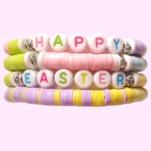 May include: A stack of four colorful bracelets with white beads spelling out "HAPPY EASTER". The bracelets are made of light green, pink, light blue, and purple beads.