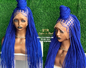 May include: A vibrant blue braided wig with a bun on top. The wig features a lace front and long, flowing braids. The text "STR Styles to Rock" is visible, along with a website and phone number.