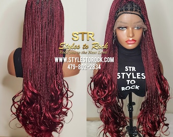 May include: A burgundy braided wig with curly ends. The wig is on a mannequin head and has a lace front. The wig is styled in a high ponytail. The text "STR Styles to Rock" is visible on the image.