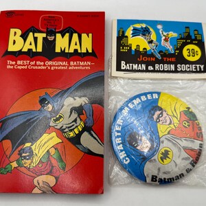 May include: A collection of vintage Batman memorabilia, including a comic book with Batman and Robin illustrations, a Batman & Robin Society card, and a Charter Member button. The comic book is red with yellow text.