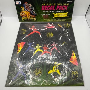 Może przedstawiać: Zestaw 24 naklejek Power Rangers Deluxe. Zestaw zawiera 2 arkusze naklejek i 1 arkusz tła z postacią. Naklejki przedstawiają postacie Power Rangers w ich ikonicznych pozach i kolorach. Zestaw wykonany jest z trwałego winylu i idealnie nadaje się do dodania odrobiny Power Rangers do każdej powierzchni.