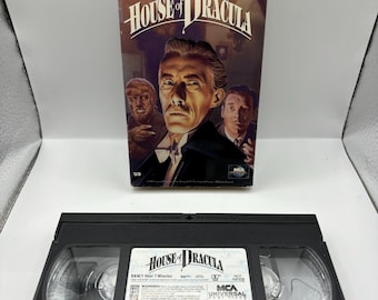 May include: A black VHS tape with a label that reads "House of Dracula" and "B&W/1 Hour 7 Minutes". The tape is from the MCA Universal Home Video collection.