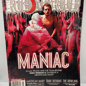 Puede incluir: Una portada de revista "RUE MORGUE" con el título en letras blancas goteando sobre un fondo rojo. La portada presenta la palabra "MANIAC" en letras blancas grandes, con una foto de un hombre y figuras. Texto adicional incluye "Elijah Wood".