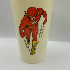 May include: A white plastic cup with a red and yellow image of The Flash running. The Flash is wearing a red suit with a yellow lightning bolt on the chest.