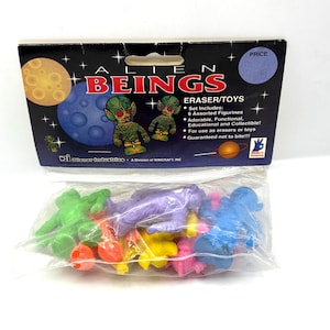 May include: A packet of "Alien Beings" eraser/toys. The packaging has a black background with planets and alien figures. Inside, a clear plastic bag contains six assorted colourful alien figurines in green, purple, blue, yellow, orange, and pink.