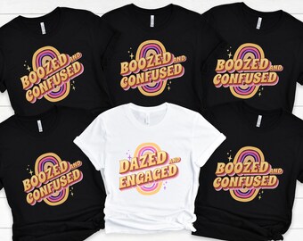 May include: Five black t-shirts with a rainbow design and the text "Boozed and Confused" and one white t-shirt with a rainbow design and the text "Dazed and Engaged".