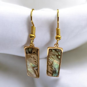 Peut inclure: Une paire de boucles d'oreilles en or avec des accents rectangulaires en nacre d'ormeau. Les boucles d'oreilles ont un design simple et élégant.
