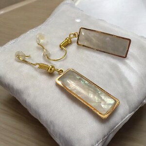 May include: A pair of gold earrings with rectangular white mother-of-pearl stones.