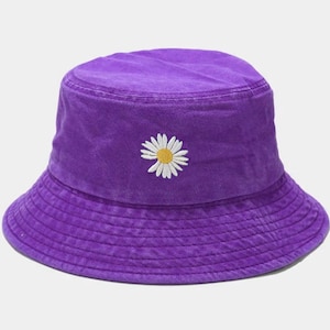 May include: A purple bucket hat with a white daisy embroidered on the front.