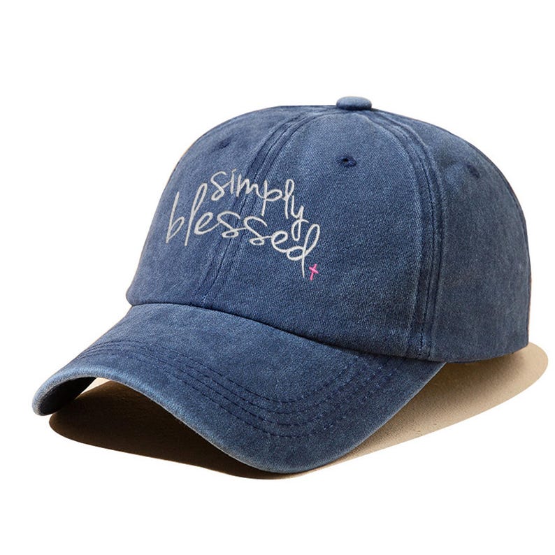 Pu&ograve; includere: Un cappello da baseball in denim blu con le parole "Simply Blessed" ricamate in bianco sul davanti. Una piccola croce rosa &egrave; ricamata accanto al testo.