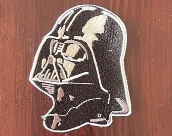 May include: Black and white embroidered patch of Darth Vader's helmet from Star Wars.