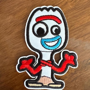 May include: A white embroidered patch of Forky from the Toy Story movie. Forky is a spork with googly eyes, a red smile, and red arms. He is wearing a blue shirt and has a white band around his head.