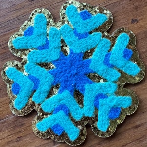 May include: A gold glitter snowflake with blue and turquoise fuzzy details.