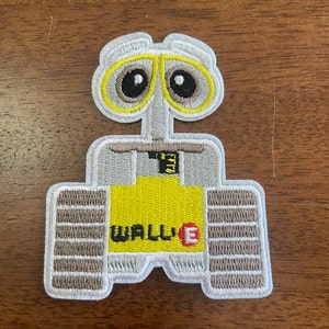 May include: Embroidered patch featuring the WALL-E robot character. The patch has a gray body, yellow accents, and the WALL-E logo. The design includes brown treads and a white border.