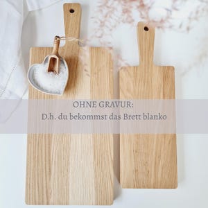 May include: Two wooden cutting boards with handles, one rectangular and one square, are displayed. A heart-shaped dish filled with salt and a small wooden scoop are on the left. The text "OHNE GRAVUR: D.h. du bekommst das Brett blanko" is visible.