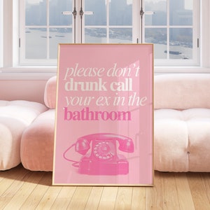 Op de afbeelding: Roze ingelijste poster met de tekst "please don't drunk call your ex in the bathroom" en een roze draaischijftelefoon illustratie.