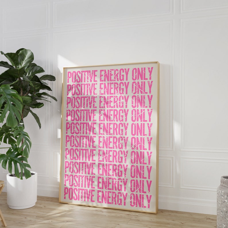 Może przedstawiać: Wydruk w ramie z tekstem "POSITIVE ENERGY ONLY" powt&oacute;rzonym r&oacute;żowymi literami na białym tle.