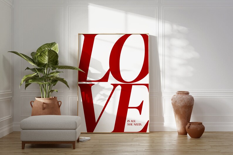 May include: A white poster with the word "LOVE" in large, red letters. The letters are stacked on top of each other. Below the word "LOVE" is the text "is all you need."