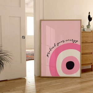 May include: A pink and white abstract print with a black circle in the center. The print is framed and has the text "protect your energy" written in black.