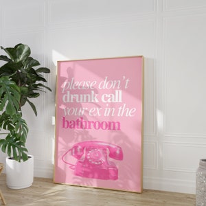 Op de afbeelding: Roze poster met de tekst "please don't drunk call your ex in the bathroom" en een roze draaischijftelefoon.