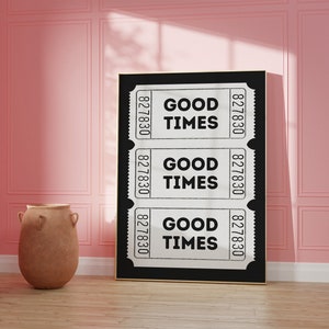 May include: Black and white print of three vintage ticket stubs with the text "GOOD TIMES" repeated on each ticket. The print is framed and hanging on a pink wall.
