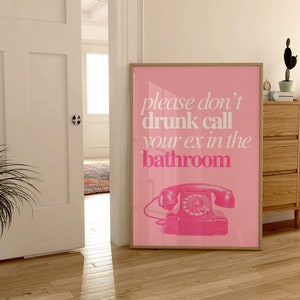 Op de afbeelding: Roze poster met de tekst "please don't drunk call your ex in the bathroom" en een roze draaischijftelefoon.