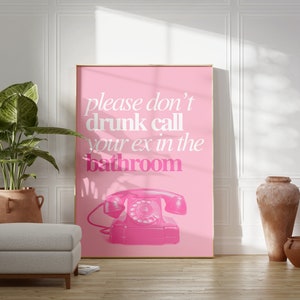 Op de afbeelding: Een roze poster met de tekst "please don't drunk call your ex in the bathroom" in witte tekst. Een roze draaischijftelefoon bevindt zich onderaan in het midden van de poster.