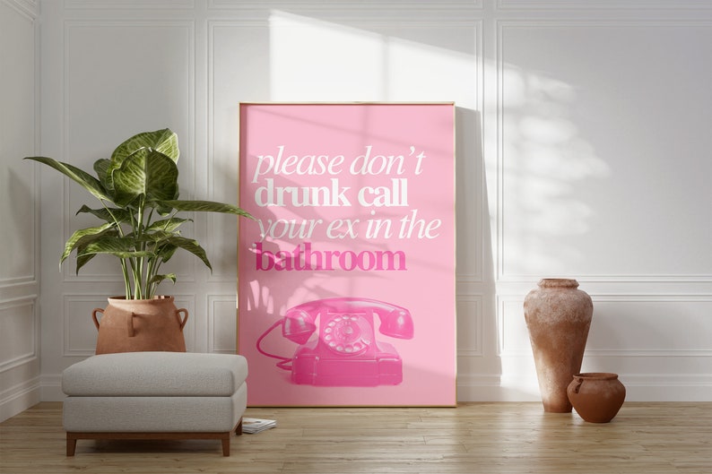 Op de afbeelding: Een roze poster met de tekst "please don't drunk call your ex in the bathroom" in witte tekst. Een roze draaischijftelefoon bevindt zich onderaan in het midden van de poster.
