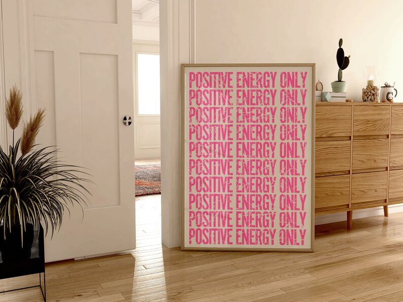 Może przedstawiać: Wydruk w ramie z tekstem "POSITIVE ENERGY ONLY" powt&oacute;rzonym r&oacute;żowymi literami na białym tle.