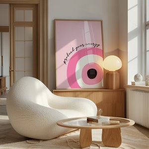 May include: A white, fluffy armchair sits in a living room with a wooden coffee table and a pink framed print with the text "protect your energy".