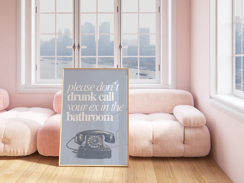 May include: A framed poster with a light blue background and white text that reads "please don't drunk call your ex in the bathroom". A black rotary phone is pictured below the text.