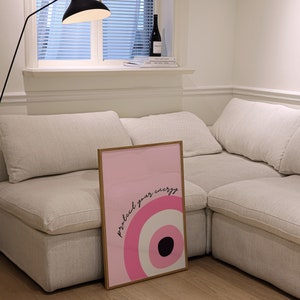 May include: A framed pink and white poster with a black circle and the text "protect your energy" in black lettering.