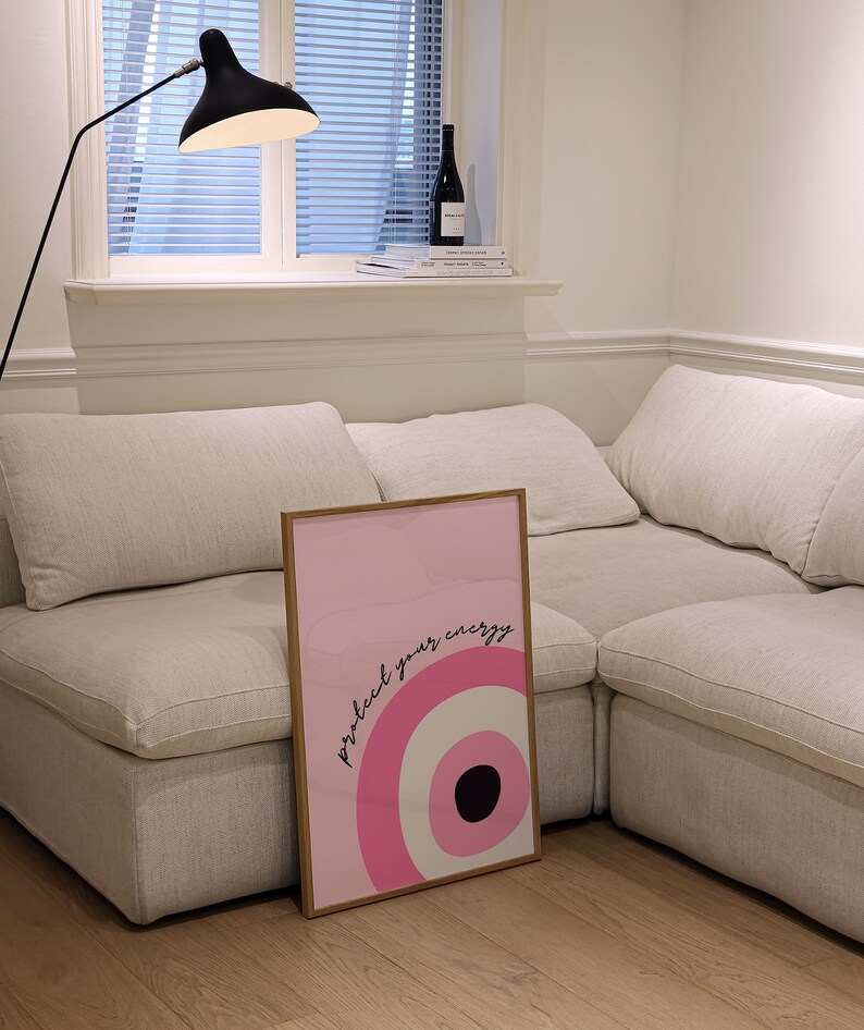 May include: A framed pink and white poster with a black circle and the text "protect your energy" in black lettering.